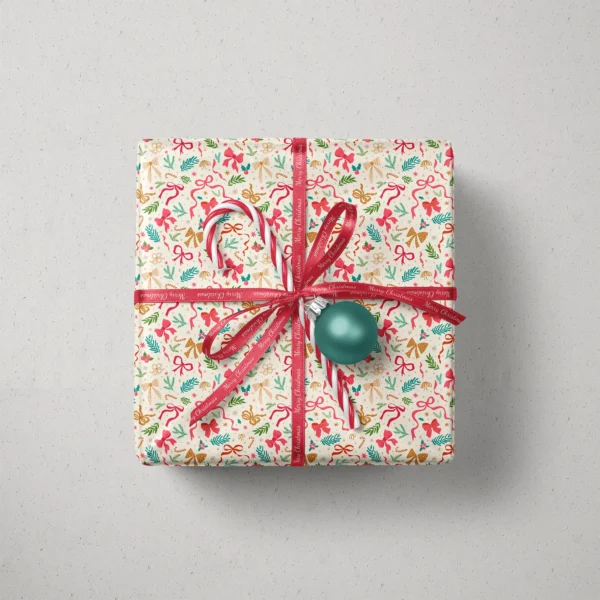 Top view of a gift in ribbon and greenery paper with a ribbon, candy canes and a bauble