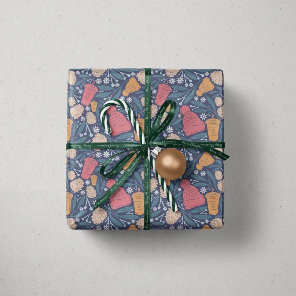 Top view of a gift in navy cozy winter paper with a ribbon, a candy cane and a bauble