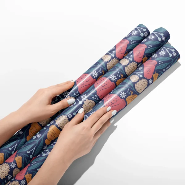 Hands smoothing three rolls of navy cozy winter wrapping paper on a white table