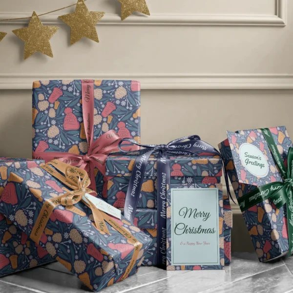 Stack of presents in navy cozy winter paper with ribbons and a Merry Christmas card by a beige wall