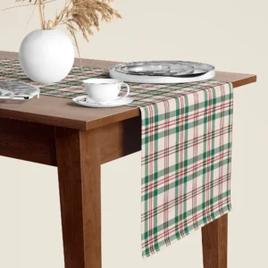 Cream, green and red plaid Christmas table runner hanging over the end of a walnut dining table, close-up