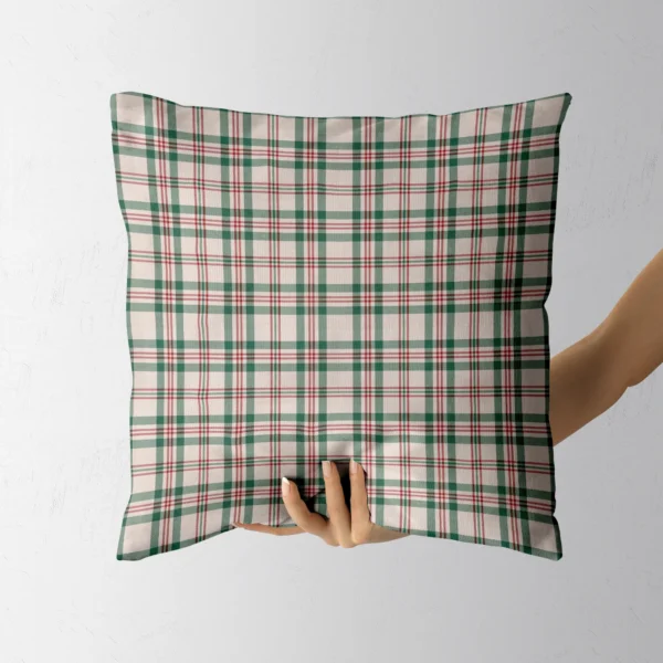 A hand holding the ivory plaid throw pillow