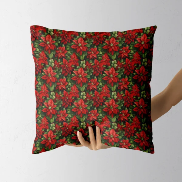 Hand holding the square pillow with red poinsettias on dark green