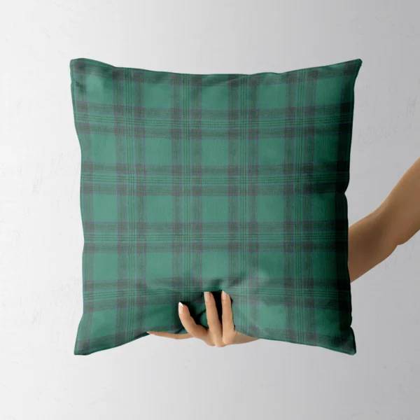 Hand holding the emerald tartan throw pillow