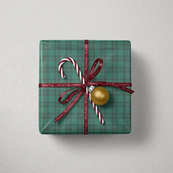 Top view of a gift in emerald green tartan paper with a ribbon, candy canes and a bauble