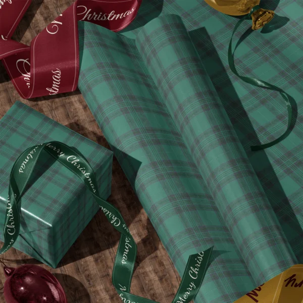 Rolls of emerald green tartan gift wrap and a wrapped box with satin ribbons on a wooden floor