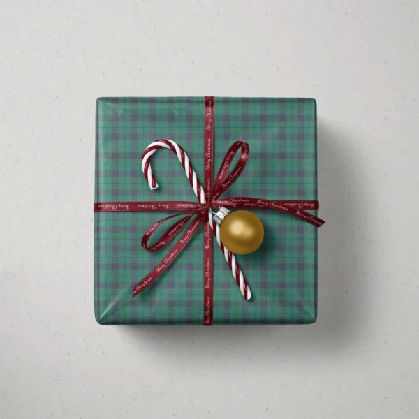 Top view of a gift in emerald and navy check paper with a ribbon, candy canes and a bauble