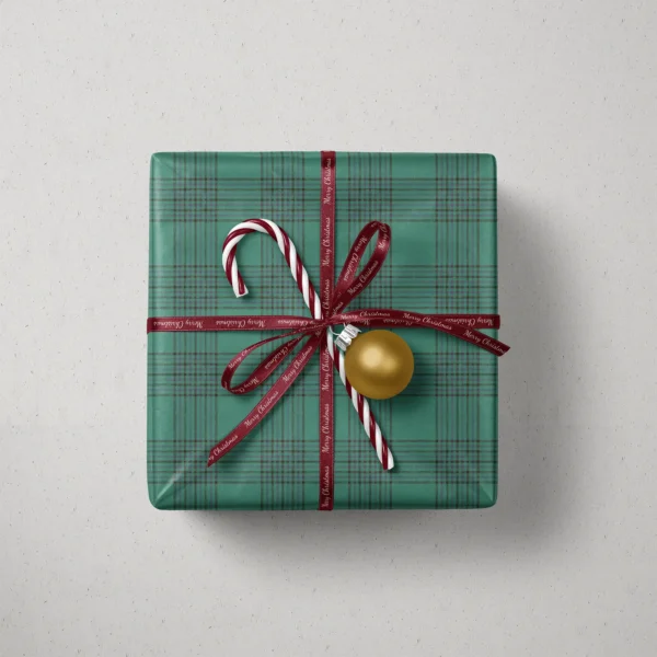 Top view of a gift in emerald windowpane plaid paper with a ribbon, candy canes and a bauble