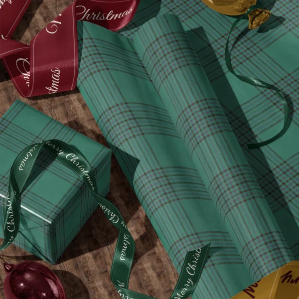 Rolls of emerald windowpane plaid gift wrap and a wrapped box with satin ribbons on a wooden floor