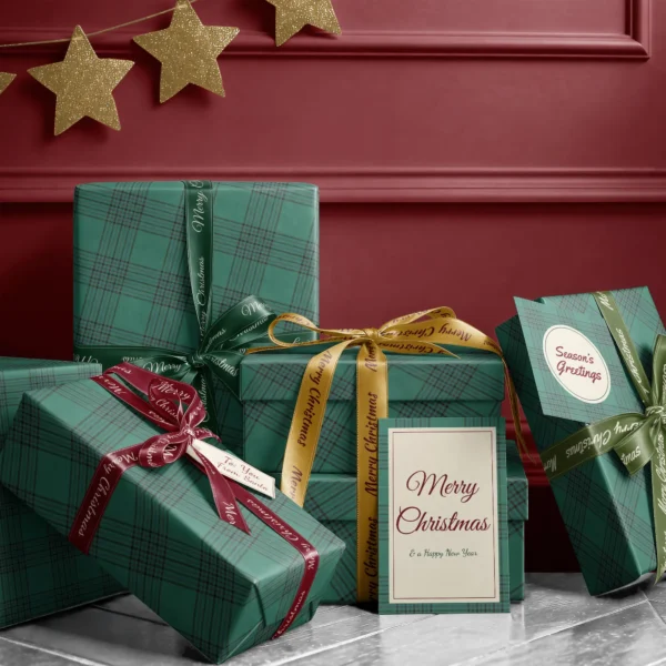 Stack of presents in emerald windowpane plaid paper with ribbons and a Merry Christmas card by a burgundy wall