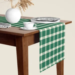 Evergreen gingham Christmas table runner hanging over the end of a walnut dining table, close-up