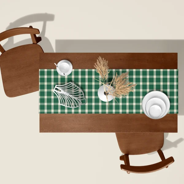 Evergreen gingham Christmas table runner seen from above on a walnut table with white dishes and dried pampas