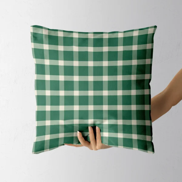 A hand holding the all-green gingham throw pillow
