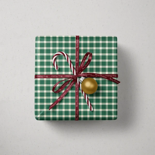Top view of a gift in evergreen gingham paper with a ribbon, candy canes and a bauble