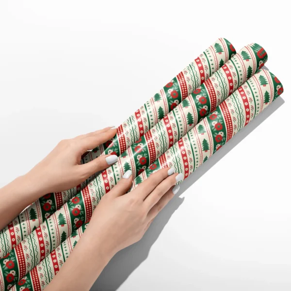 Hands smoothing three rolls of folk border wrapping paper on a white table
