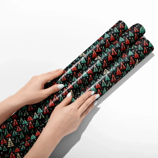 Hands smoothing three rolls of black folk tree wrapping paper on a white table