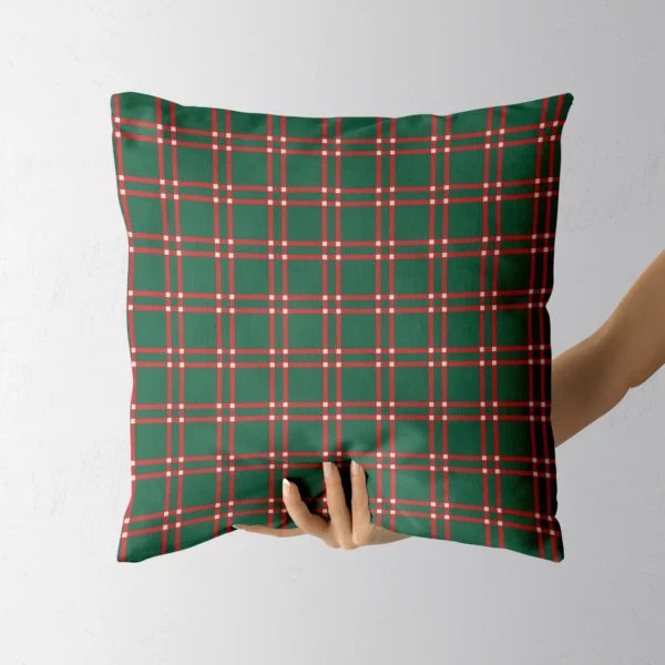 Hand holding the dark green plaid throw pillow