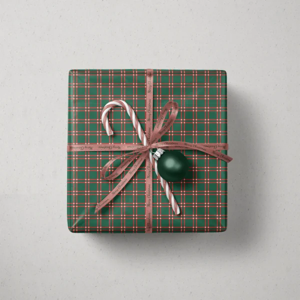 Top view of a gift in green windowpane plaid paper with a ribbon, candy canes and a bauble
