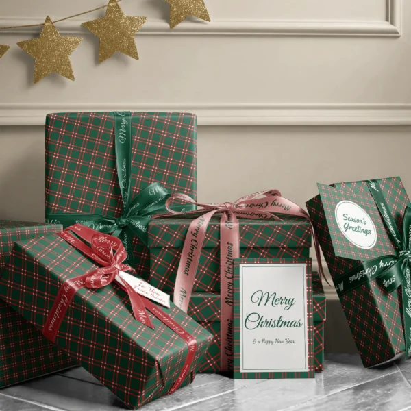 Stack of presents in green windowpane plaid paper with ribbons and a Merry Christmas card by a cream wall