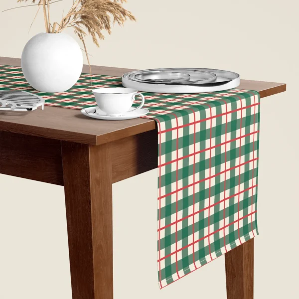 Green check Christmas table runner hanging over the end of a walnut dining table, close-up