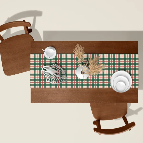 Green check Christmas table runner seen from above on a walnut table with white dishes and dried pampas