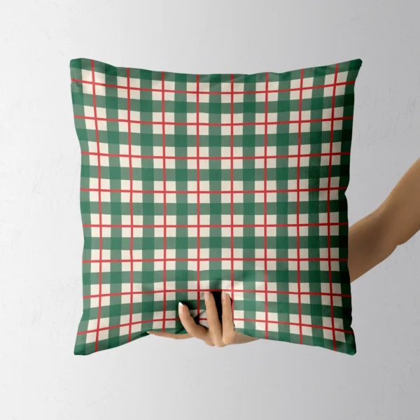 Hand holding the green gingham throw pillow with red windowpane lines
