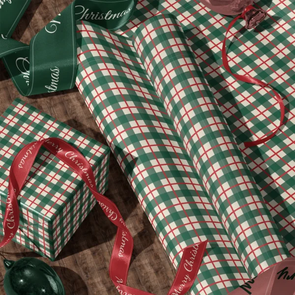 Rolls of green and red check gift wrap and a wrapped box with satin ribbons on a wooden floor