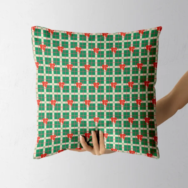 Hand holding the green check pillow with red bows