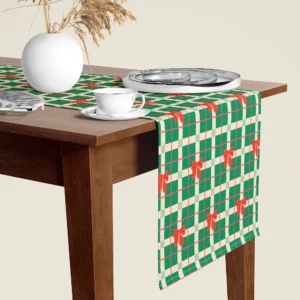 Green plaid with red bows Christmas table runner hanging over the end of a walnut dining table, close-up