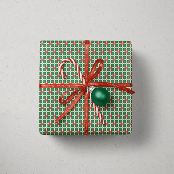 Top view of a gift in green plaid bow paper with a ribbon, candy canes and a bauble