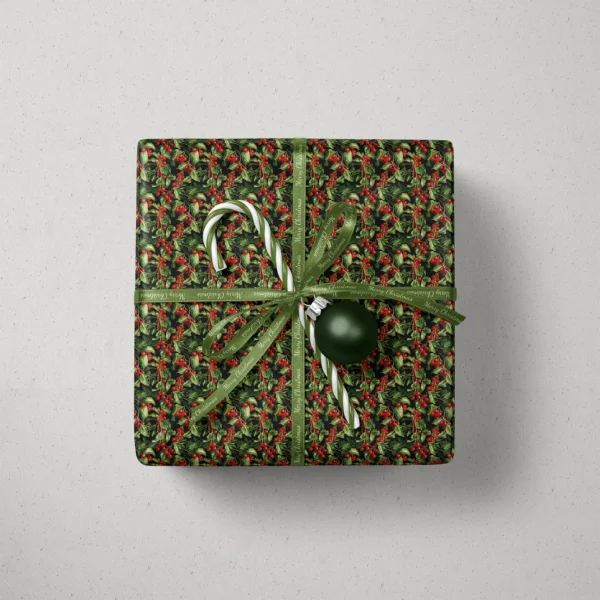 Top view of a gift in black holly berry paper with a ribbon, a candy cane and a bauble