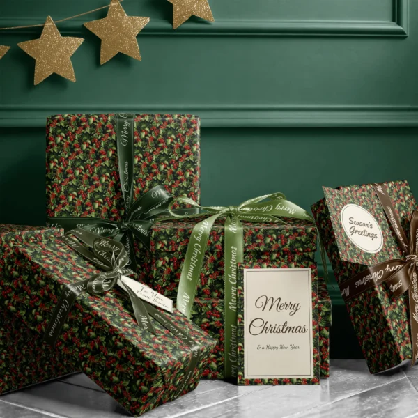 Stack of presents in black holly berry paper with ribbons and a Merry Christmas card by a dark green wall