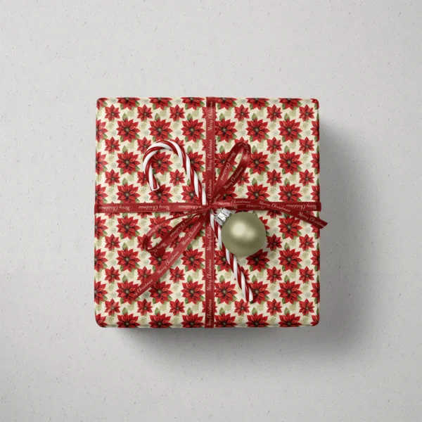 Top view of a gift in large cream poinsettia paper with a ribbon, a candy cane and a bauble