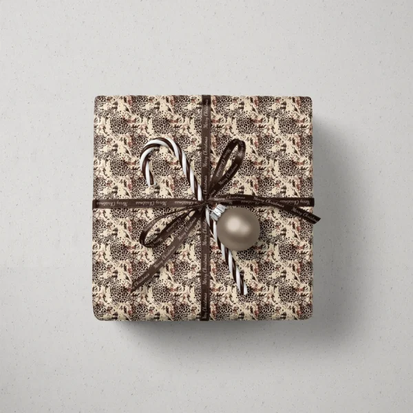 Top view of a gift in brown leopard paper with a ribbon, a candy cane and a bauble