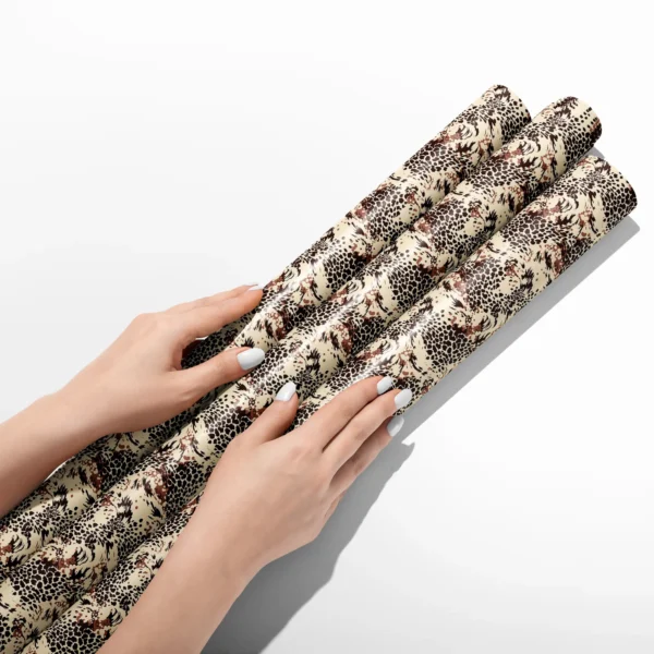 Hands smoothing three rolls of brown leopard wrapping paper on a white table