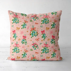 Blush mistletoe Christmas pillow facing forward on a white floor