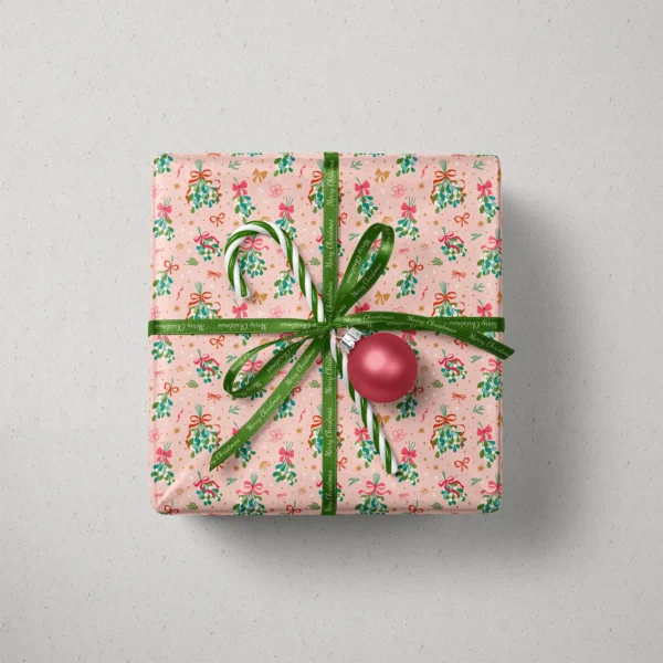 Top view of a gift in mistletoe paper with a ribbon, candy canes and a bauble