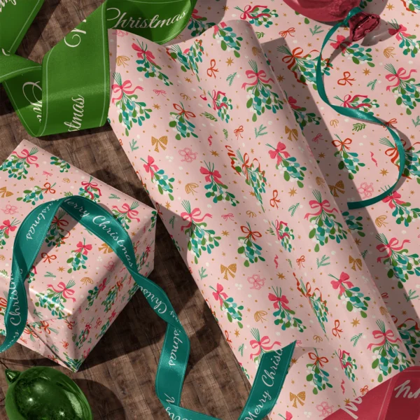 Rolls of mistletoe gift wrap and a wrapped box with satin ribbons on a wooden floor