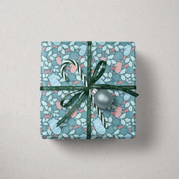 Top view of a gift in teal mitten paper with a ribbon, a candy cane and a bauble