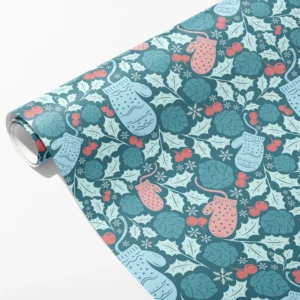 Roll of teal wrapping paper with pink and pale blue mittens, holly, coral berries and snowflakes, partly unrolled on white