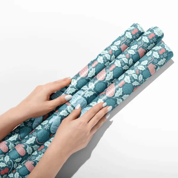 Hands smoothing three rolls of teal mitten wrapping paper on a white table