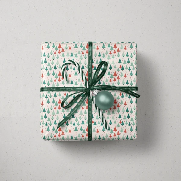Top view of a gift in white dotted tree paper with a ribbon, a candy cane and a bauble