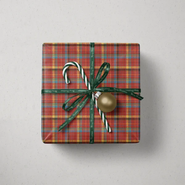 Top view of a gift in multicolor plaid paper with a ribbon, candy canes and a bauble