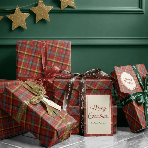 Stack of presents in multicolor plaid paper with ribbons and a Merry Christmas card by a dark green wall