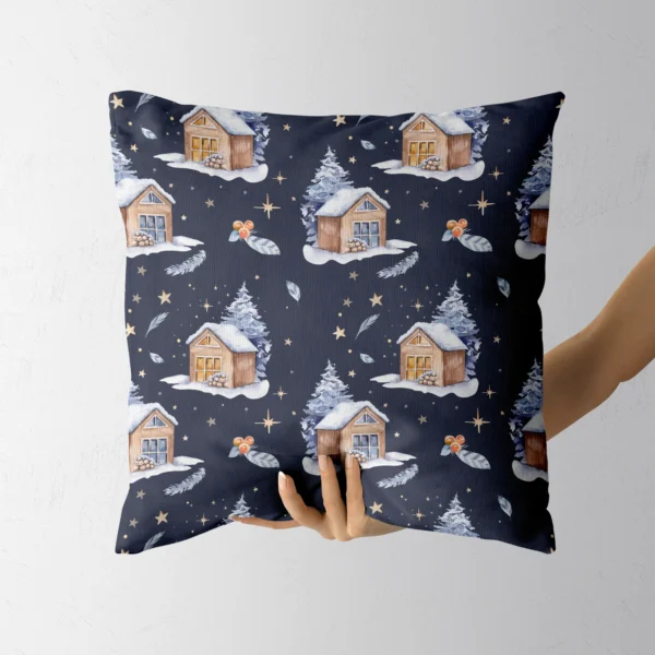 Hand holding the navy pillow with snowy cabins and gold stars