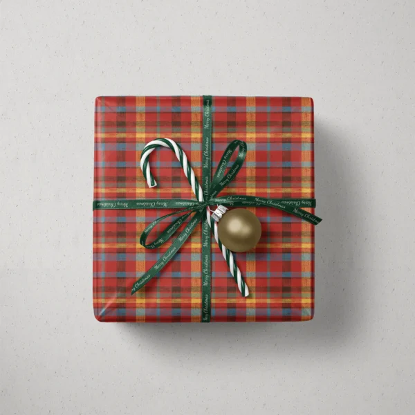 Top view of a gift in patchwork plaid paper with a ribbon, candy canes and a bauble