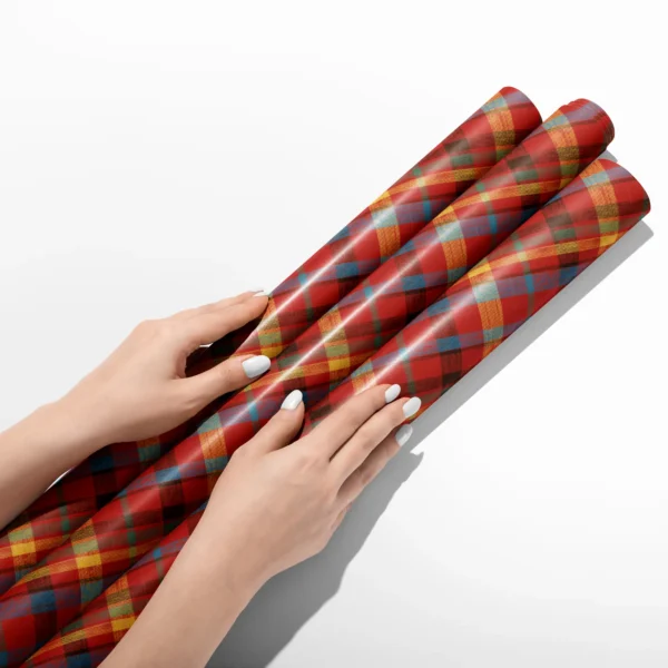 Hands smoothing three rolls of patchwork plaid wrapping paper on a white table