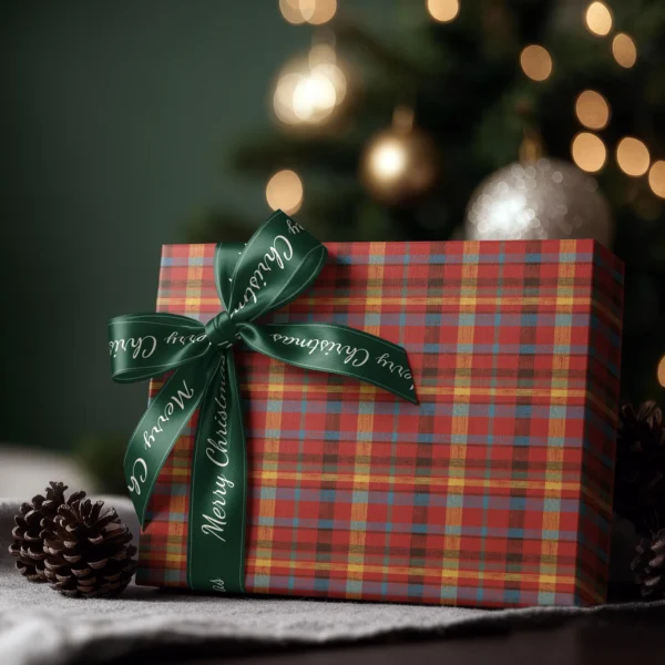 Box wrapped in patchwork plaid paper with a satin ribbon bow, Christmas tree lights behind