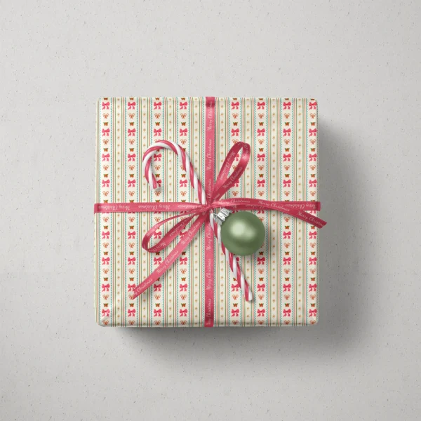 Top view of a gift in pink bow stripe paper with a ribbon, candy canes and a bauble