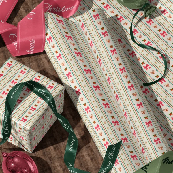 Rolls of pink bow stripe gift wrap and a wrapped box with satin ribbons on a wooden floor